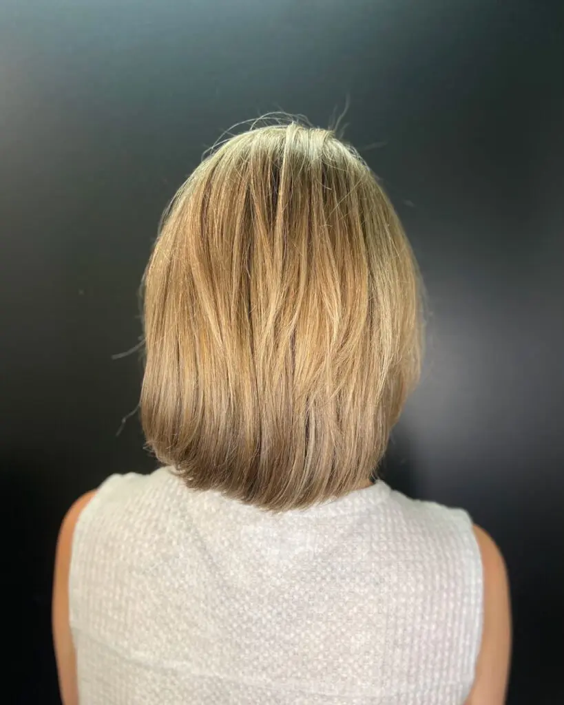 View from the back of a dimensional honey blonde bob haircut with soft texture and an inward beveled finish, styled at Sunday Salon in Raleigh, NC.