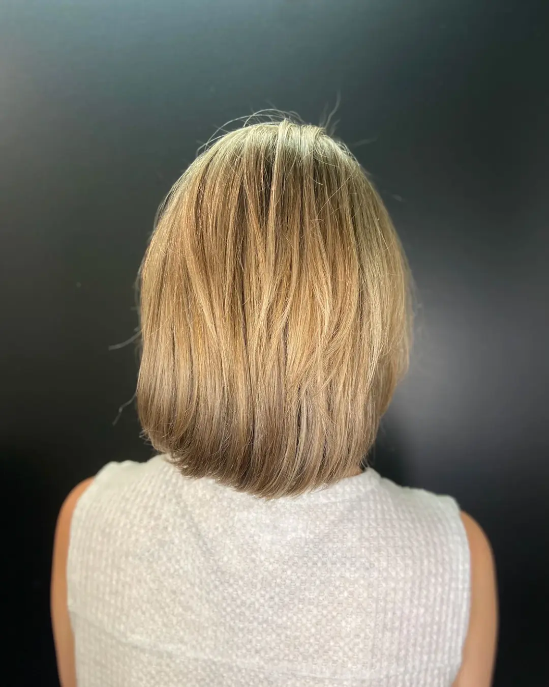Dimensional Honey Blonde Textured Bob with a Beveled Finish View from the back of a dimensional honey blonde bob haircut with soft texture and an inward beveled finish, styled at Sunday Salon in Raleigh, NC.