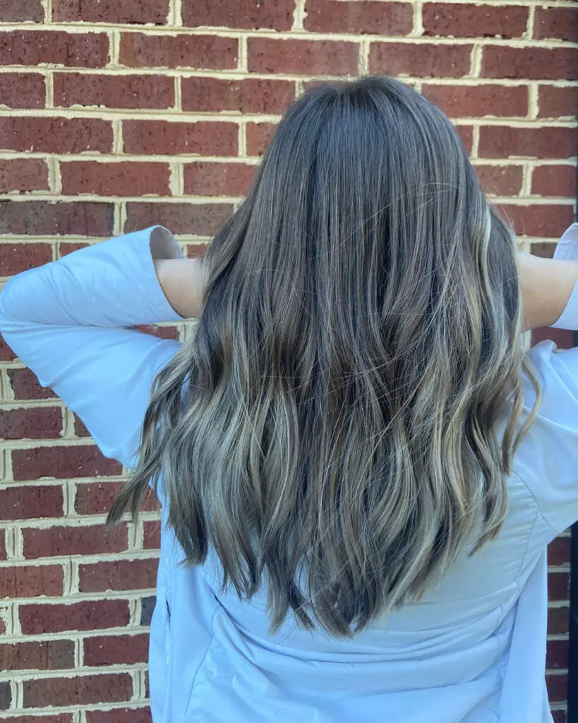 Dimensional Ash Bronde Balayage with Long Beachy Waves Back view of long, thick hair with cool ash blonde highlights over a deep brunette base, styled in loose beachy waves at Sunday Salon in Raleigh, NC.