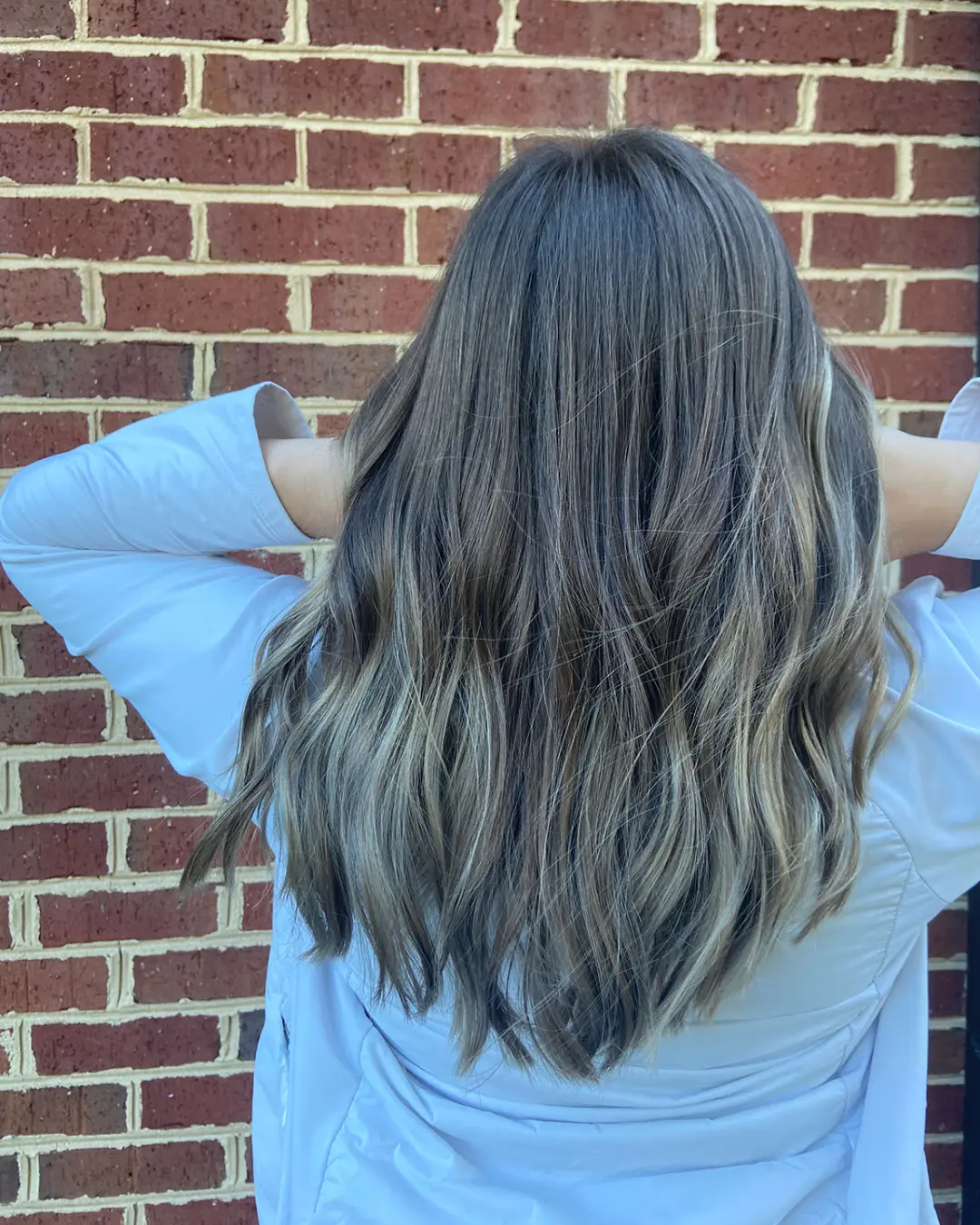 Dimensional Ash Bronde Balayage with Long Beachy Waves Back view of long, thick hair with cool ash blonde highlights over a deep brunette base, styled in loose beachy waves at Sunday Salon in Raleigh, NC.