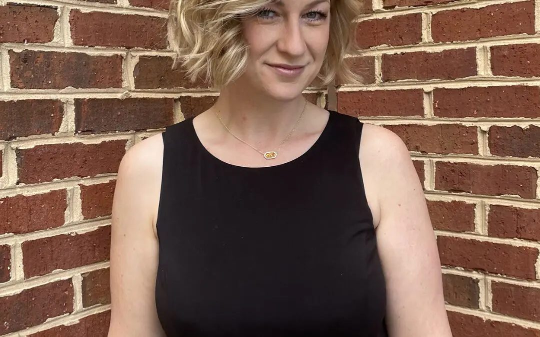 Woman with a chin-length textured bob styled in deep side-parted waves, featuring bright vanilla blonde highlights and a soft shadow root, styled at Sunday Salon in Raleigh, NC.