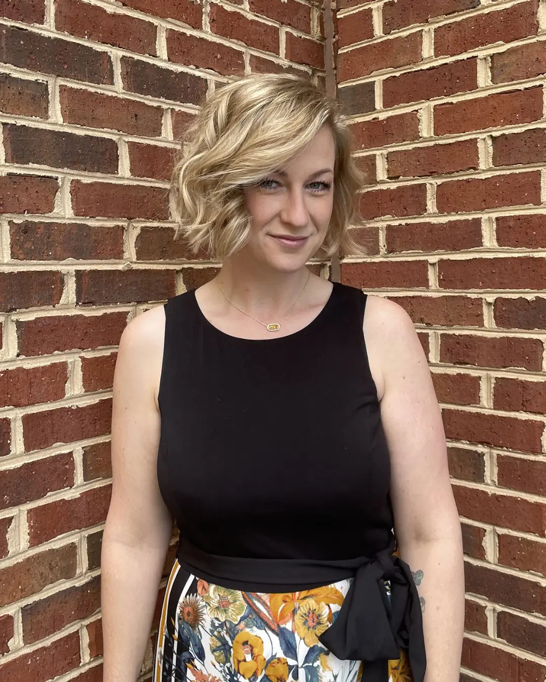 Bright Vanilla Blonde Textured Chin-Length Bob Woman with a chin-length textured bob styled in deep side-parted waves, featuring bright vanilla blonde highlights and a soft shadow root, styled at Sunday Salon in Raleigh, NC.