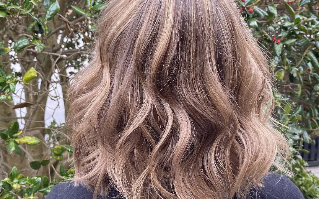Back view of a shoulder-length wavy lob featuring a custom dusty rose gold and bronde balayage with a seamless shadow root, styled at Sunday Salon in Raleigh, NC.