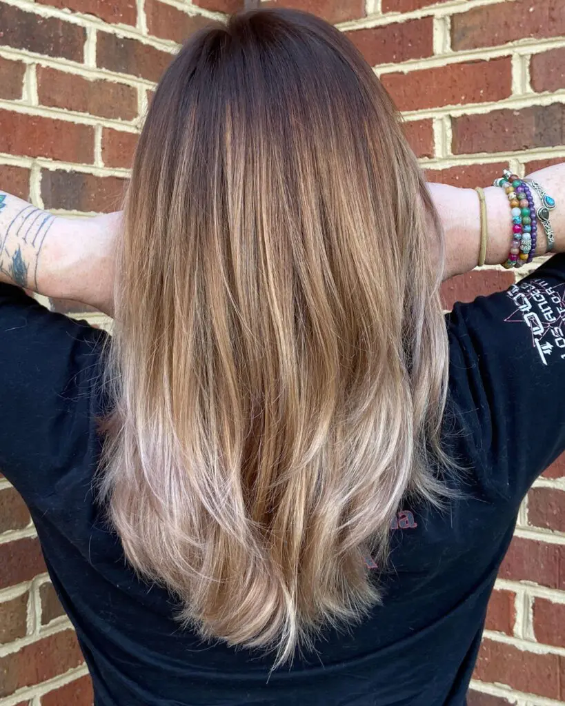Back view of straight medium-long hair featuring a dramatic color melt from a deep brunette shadow root to warm caramel mid-lengths and bright pale blonde ends, styled at Sunday Salon in Raleigh, NC.
