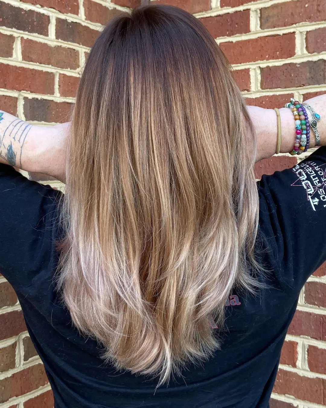 Dramatic Brunette to Pale Blonde Color Melt with Sleek Layers Back view of straight medium-long hair featuring a dramatic color melt from a deep brunette shadow root to warm caramel mid-lengths and bright pale blonde ends, styled at Sunday Salon in Raleigh, NC.