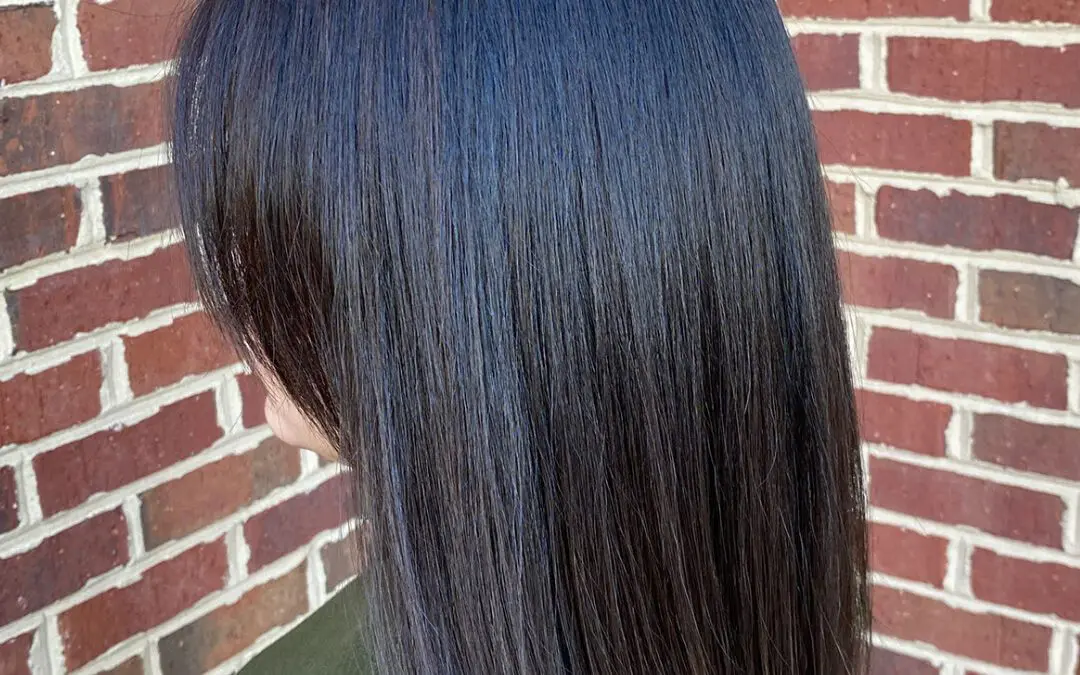 Side profile of a woman with a sleek, straight blunt collarbone-length lob featuring a high-shine midnight brunette color, styled at Sunday Salon in Raleigh, NC.