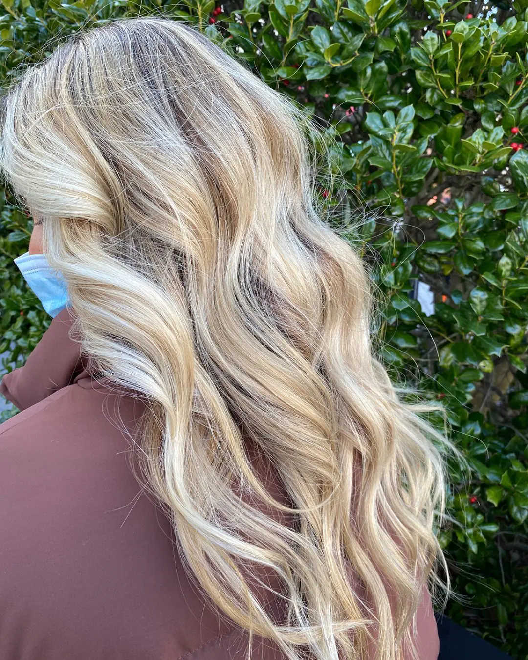 Profile view of a woman outdoors with ultra-long, thick wavy hair featuring bright creamy blonde highlights and a shadow root by Lisa Edwards at Sunday Salon in Raleigh, NC.