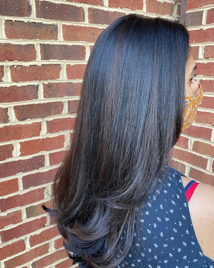 Keratin Portfolio 2 1080 x 1350 Side view of a client at Sunday Salon in Raleigh showcasing ultra-long, deep espresso brown hair. The hair has been beautifully transformed to feature impeccably sleek texture and incredible mirror-like shine, cascading past the shoulders with softly curved layered ends.