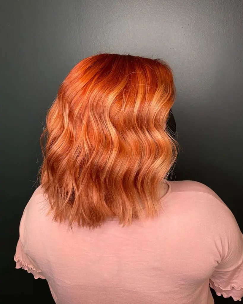 Vivid Fiery Orange and Copper Lob with Soft Waves Back view of a woman with a collarbone-length blunt lob featuring a vibrant, vivid fiery orange and copper custom color styled in soft waves at Sunday Salon in Raleigh, NC.