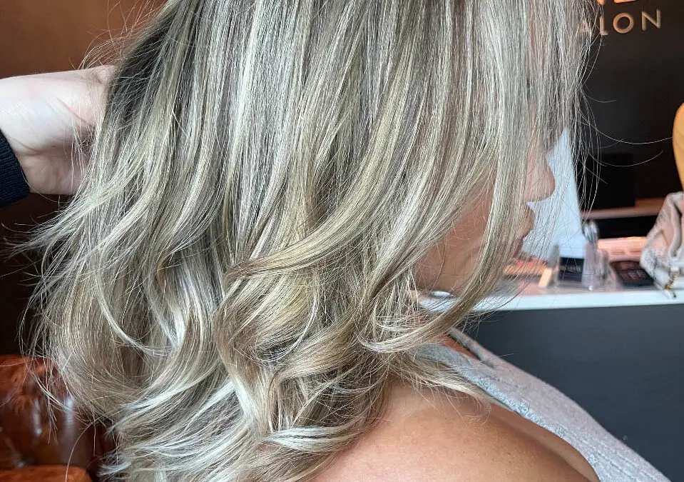 Side profile of a woman with medium-length textured layered hair showcasing a high-contrast icy vanilla and ash blonde balayage, custom colored by Lizzie Post at Sunday Salon in Raleigh, NC.