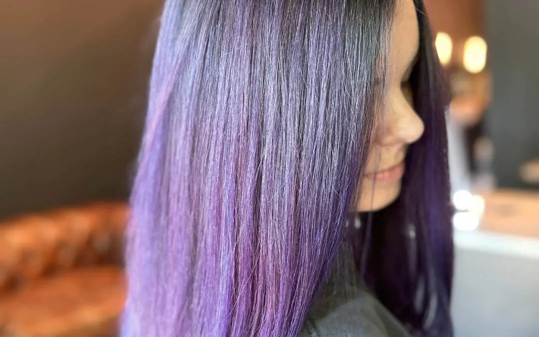 Side profile of a client showcasing sleek, medium-long straight hair with a vivid metallic purple color melt and deep shadow root, custom colored by Lisa Edwards at Sunday Salon in Raleigh, NC.