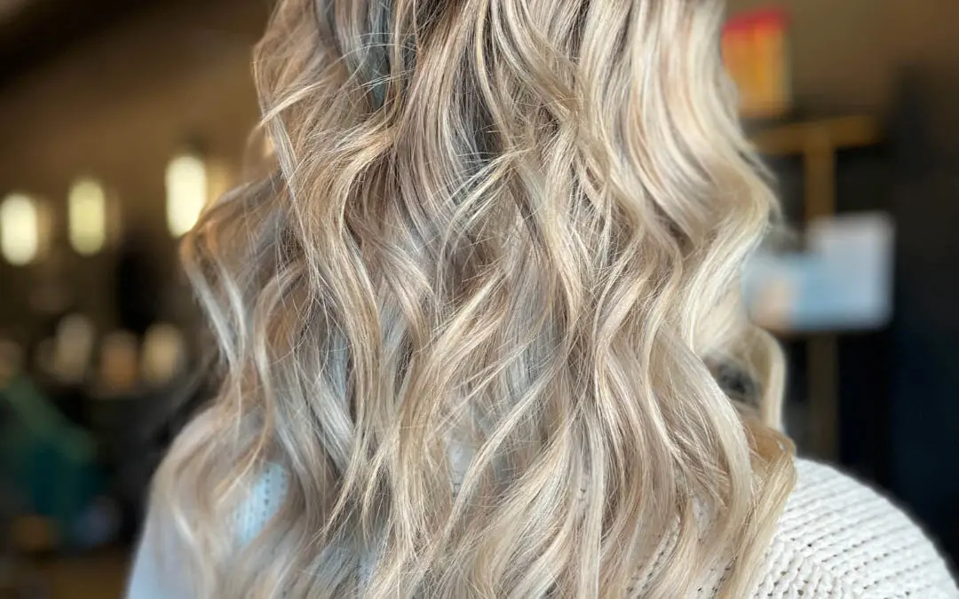 Back view of a client showcasing long dimensional vanilla and icy blonde balayage hair with a shadow root, styled in piecey beachy waves at Sunday Salon in Raleigh, NC.