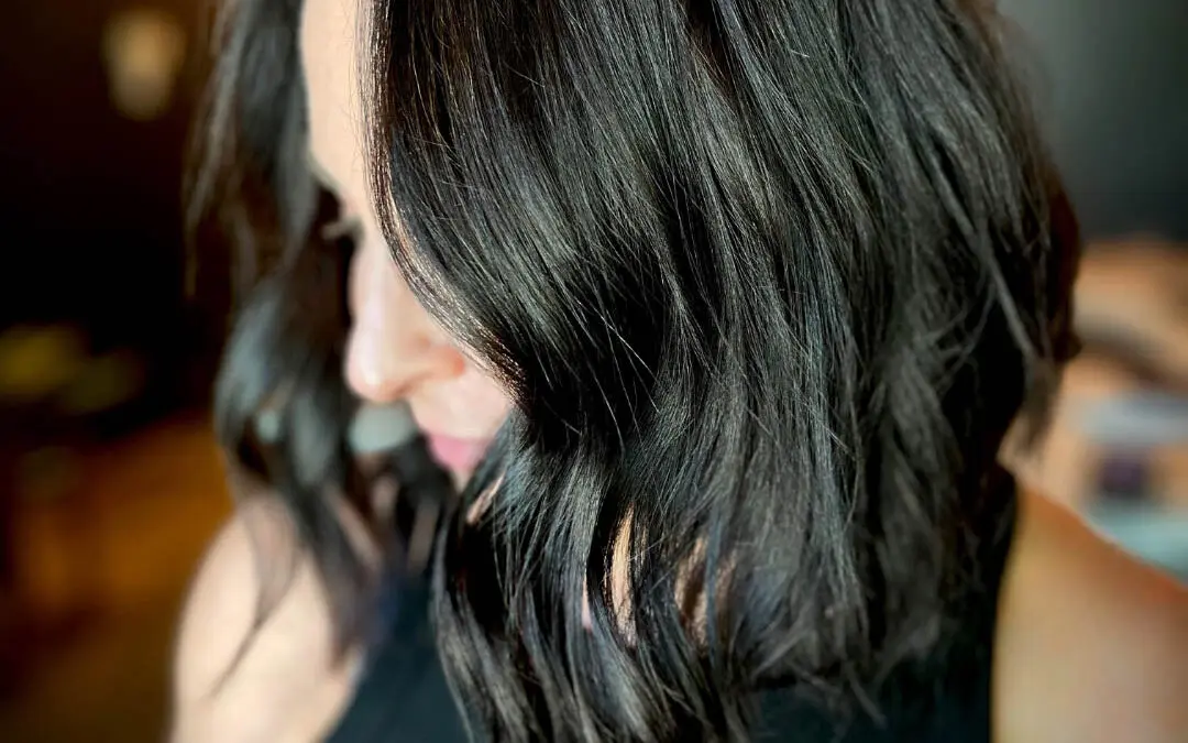 Side profile of a client showcasing a highly reflective, deep espresso collarbone-length textured lob styled in soft, undone waves at Sunday Salon in Raleigh, NC.