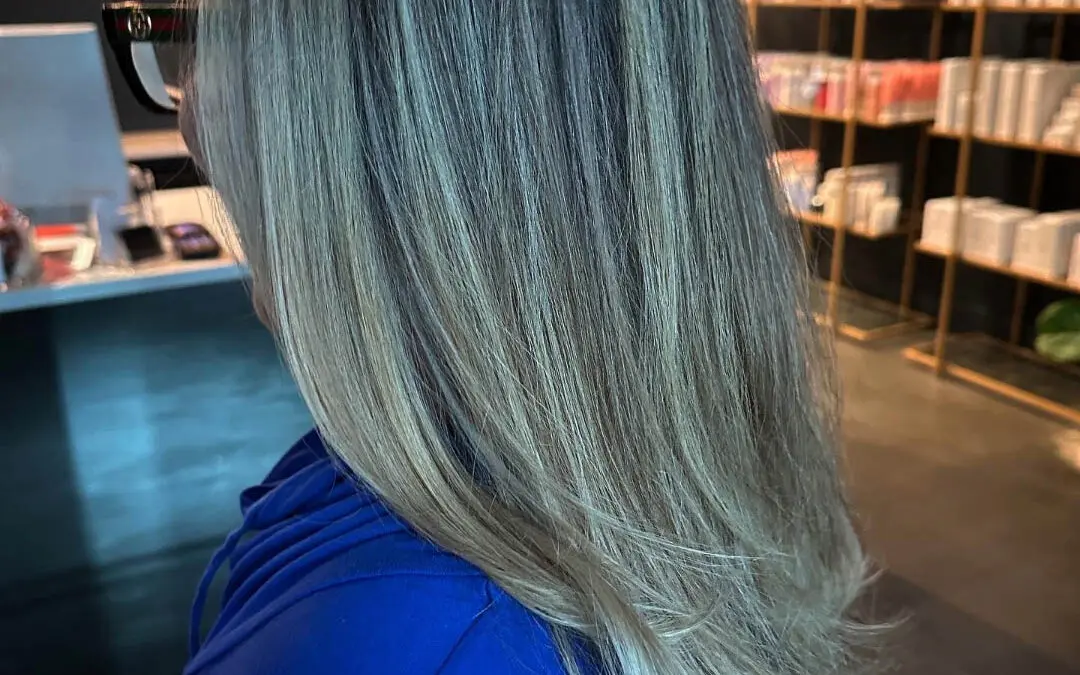 Side profile of a client showcasing long, dimensional cool-toned ash bronde hair with finely woven highlights, styled in a smooth blowout at Sunday Salon in Raleigh, NC.