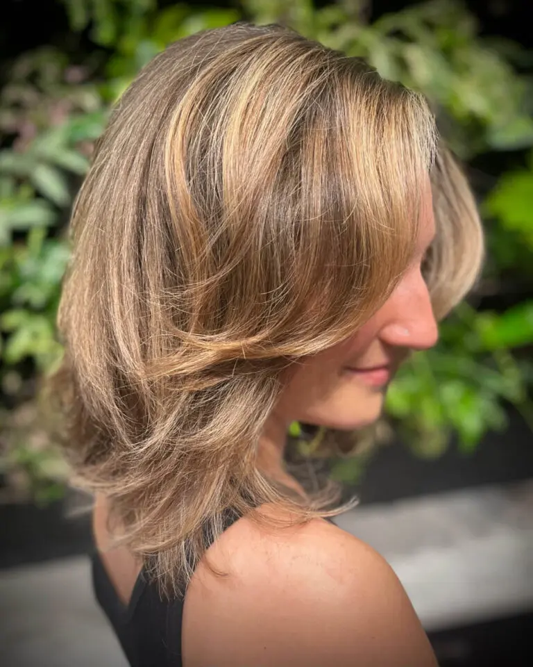 Back view of a client with defined, medium-length natural spiral curls featuring dimensional golden caramel highlights, styled to perfection at Sunday Salon in Raleigh, NC.