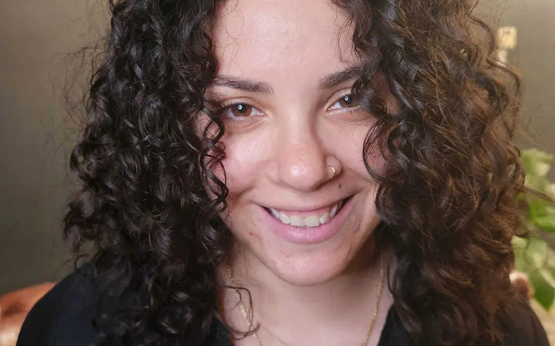 Smiling client at Sunday Salon in Raleigh showcasing a gorgeous shoulder-length curly haircut with perfectly defined, bouncy dark brunette ringlets.