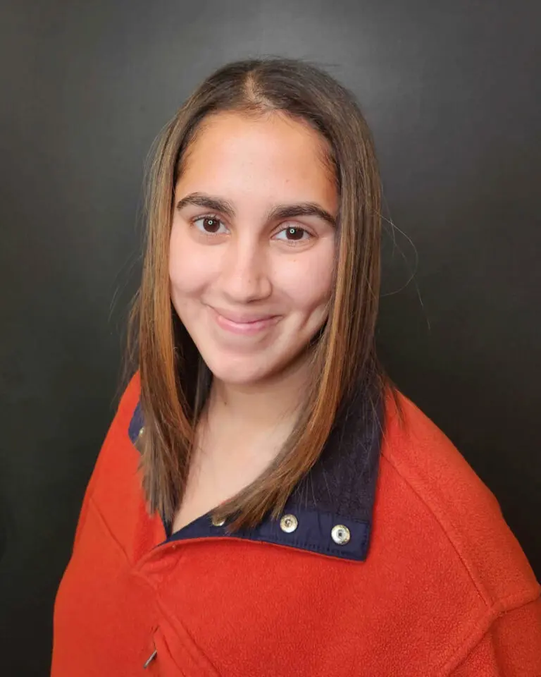 Smiling client showing off a fresh, sleek collarbone-length haircut featuring a smooth blowout and warm dimensional brunette highlights at Sunday Salon in Raleigh.