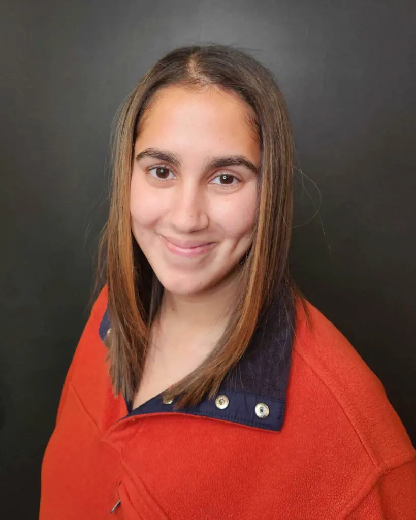 Smiling client showing off a fresh, sleek collarbone-length haircut featuring a smooth blowout and warm dimensional brunette highlights at Sunday Salon in Raleigh.