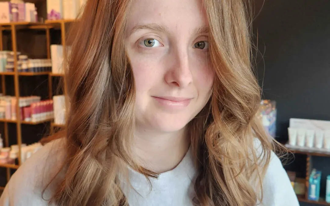 Client showcasing a mid-length haircut with warm strawberry blonde and light copper tones, featuring soft face-framing waves styled perfectly at Sunday Salon in Raleigh.