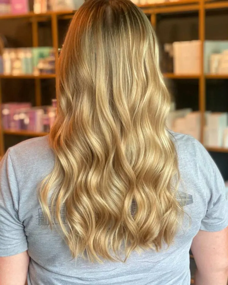Back view of a client showcasing a thick, luminous honey and cream blonde balayage on voluminous waves styled by Tyler Holden at Sunday Salon in Raleigh.