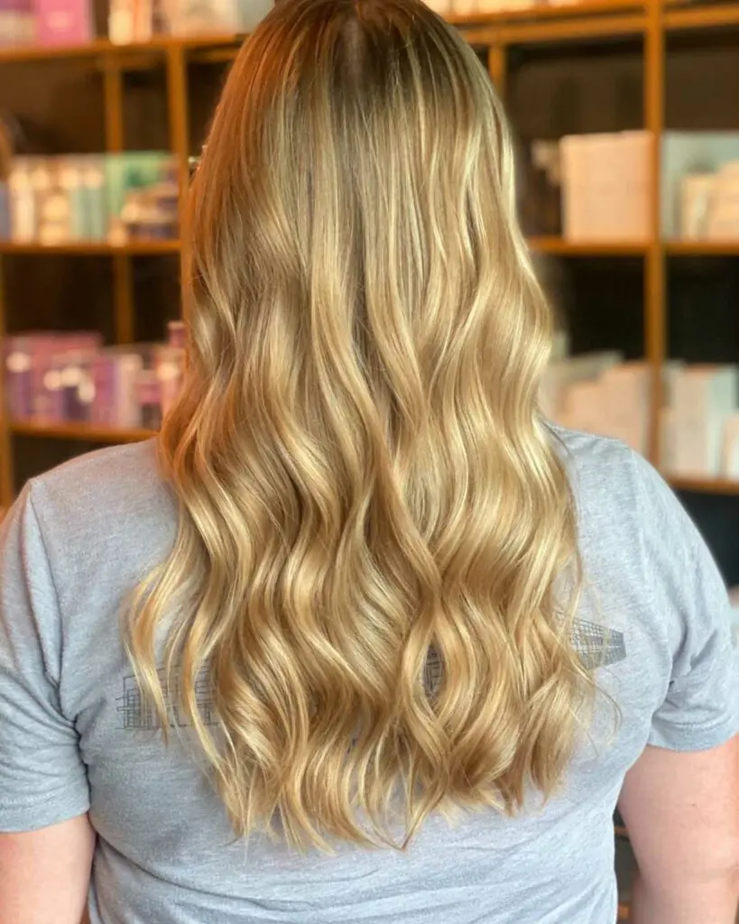 Back view of a client showcasing a thick, luminous honey and cream blonde balayage on voluminous waves styled by Tyler Holden at Sunday Salon in Raleigh.