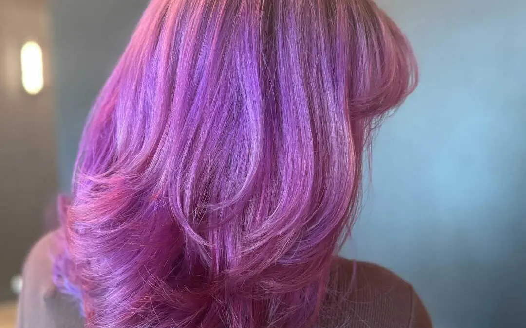 A client at Sunday Salon in Raleigh showcasing a striking vivid hair color transitioning from bright magenta to deep purple with subtle indigo ends, styled in a voluminous, heavily layered bouncy blowout.