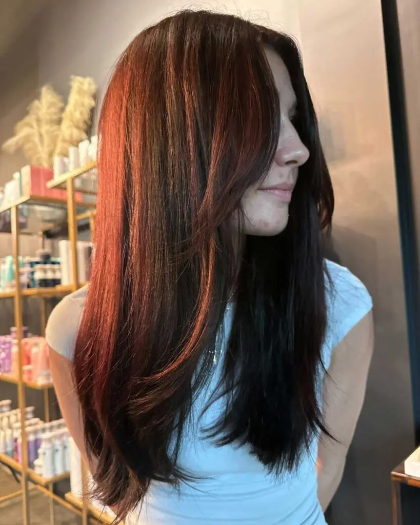 Sleek Dark Cherry Brunette with Long Face-Framing Layers A client at Sunday Salon in Raleigh showcasing a sleek, long haircut with rich dark cherry brunette color, soft face-framing layers, and a smooth blowout finish.