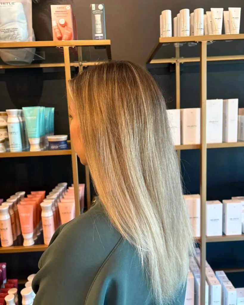 Dimensional Sandy Blonde with Sleek Long Layers A client at Sunday Salon in Raleigh showcasing mid-back length straight hair with dimensional sandy blonde highlights, a soft shadow root, and a sleek, polished finish.
