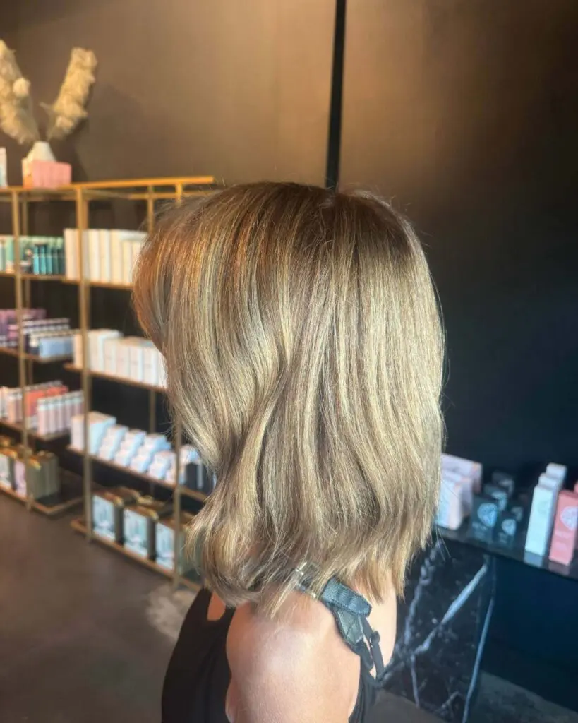 Get a chic hair transformation with honey blonde highlights and a textured lob. Our expert stylists await! Book your appointment at Sunday Salon today!