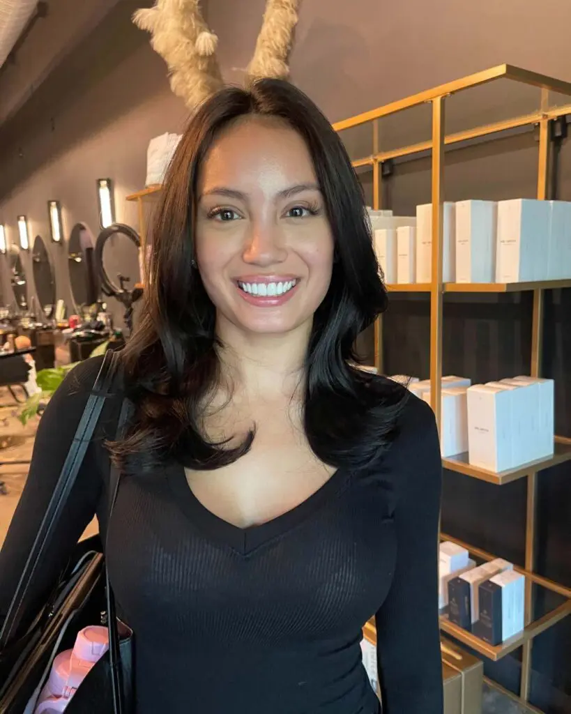 Sleek Espresso Brunette with Face-Framing Layers and a Voluminous Blowout A smiling client at Sunday Salon in Raleigh showcasing mid-length, deep espresso brunette hair with a remarkably glossy finish. The hair is styled in a sleek, voluminous blowout featuring soft, bouncy face-framing layers that enhance its natural thickness and radiant shine.