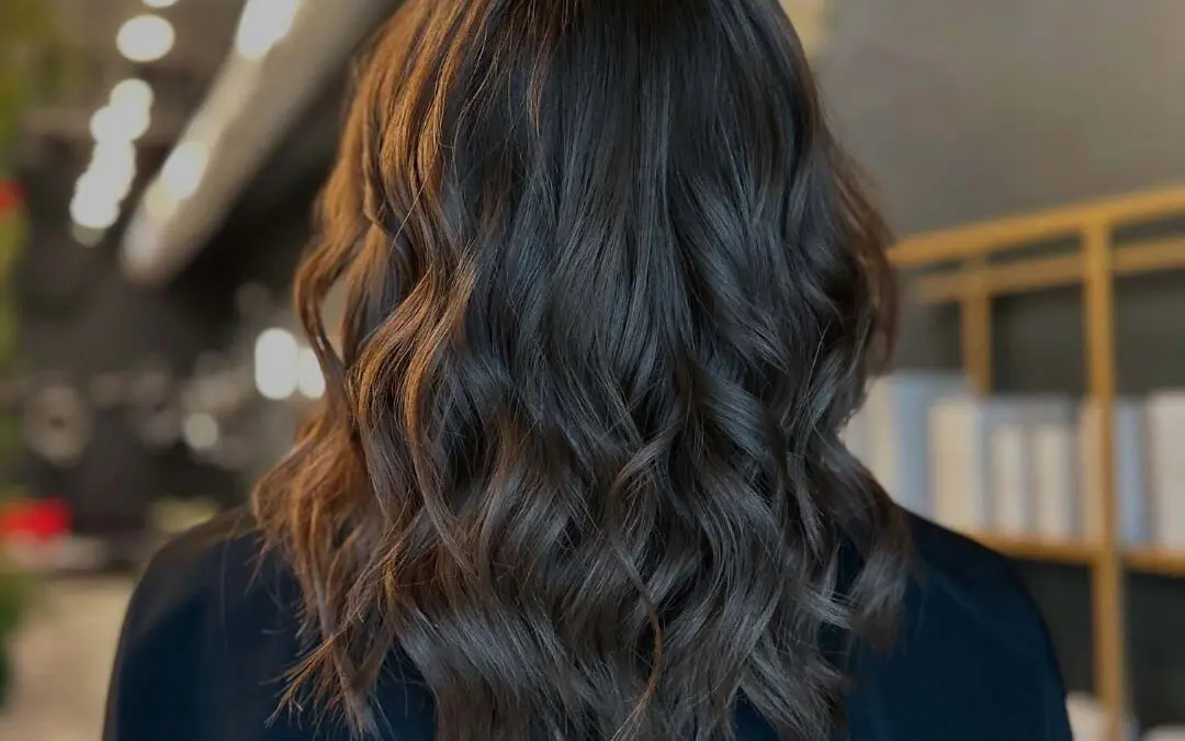 A client with a mid-length dark chocolate brunette lob styled in a voluminous blowout with bouncy, defined waves and incredible shine at Sunday Salon in Raleigh.