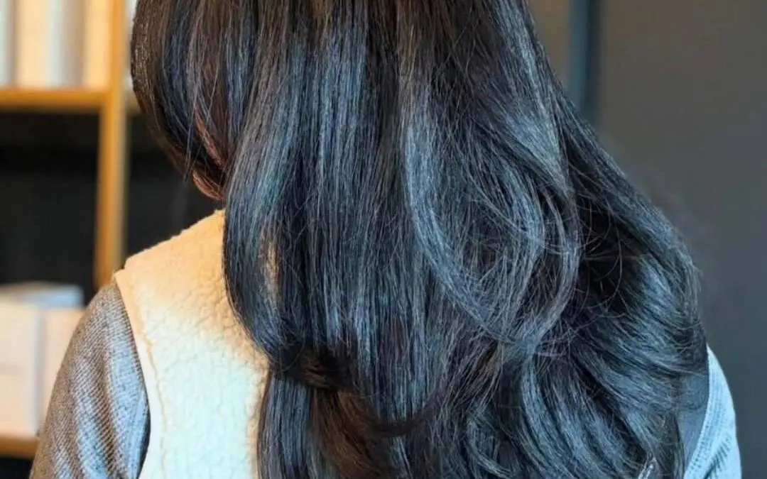 A client with long, thick, dark espresso brunette hair styled in a highly voluminous blowout with bouncy layered ends, crafted at Sunday Salon in Raleigh.