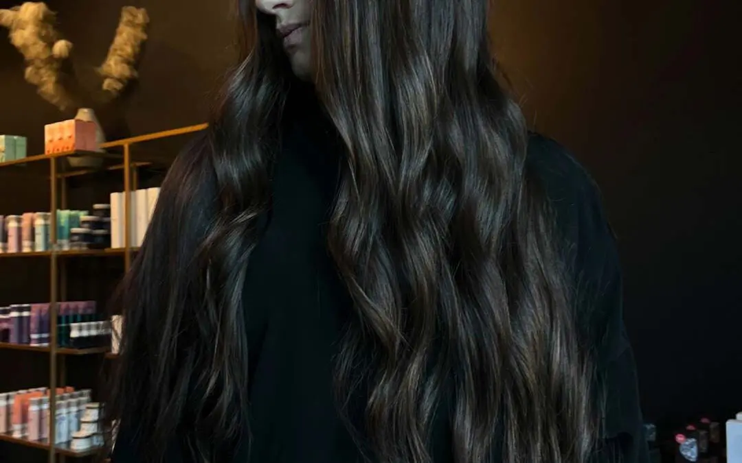 A client with ultra-long deep espresso brunette hair styled in effortless cascading waves with subtle warm dimension, created at Sunday Salon in Raleigh.