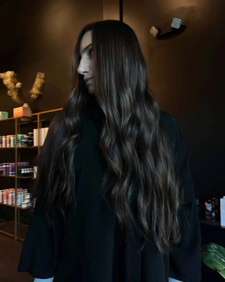 A client with ultra-long deep espresso brunette hair styled in effortless cascading waves with subtle warm dimension, created at Sunday Salon in Raleigh.