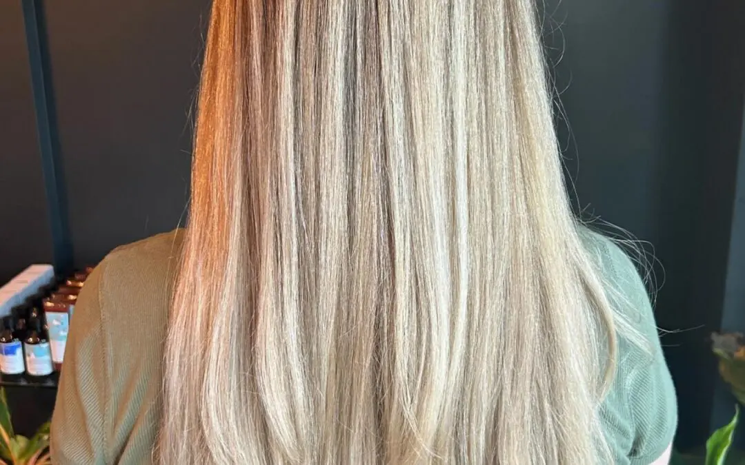 A client showcasing ultra-long, straight hair featuring a dimensional creamy vanilla blonde color and sleek sweeping layers, crafted at Sunday Salon in Raleigh.