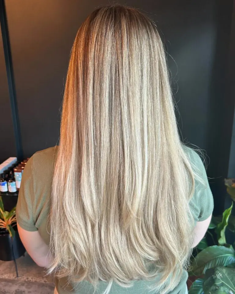 A client showcasing ultra-long, straight hair featuring a dimensional creamy vanilla blonde color and sleek sweeping layers, crafted at Sunday Salon in Raleigh.