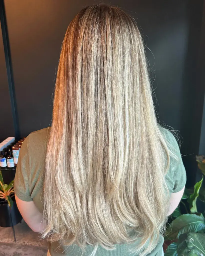 Ultra-Long Creamy Vanilla Blonde with Sleek Sweeping Layers A client showcasing ultra-long, straight hair featuring a dimensional creamy vanilla blonde color and sleek sweeping layers, crafted at Sunday Salon in Raleigh.
