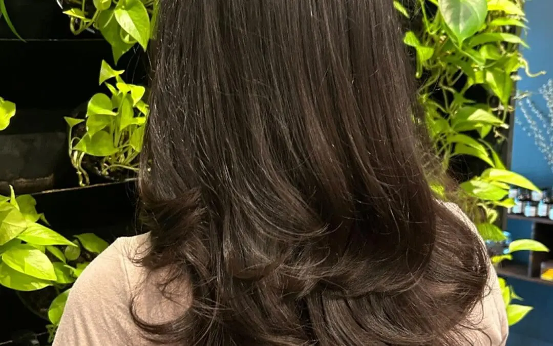 A client with thick, long dark chocolate brunette hair styled in a voluminous blowout with bouncy, highly textured layered ends at Sunday Salon in Raleigh.