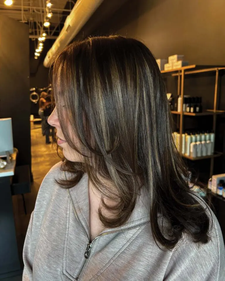 Medium-length dark brunette hair styled sleekly with face-framing layers and striking dimensional caramel highlights, expertly crafted by a stylist at Sunday Salon in Raleigh.