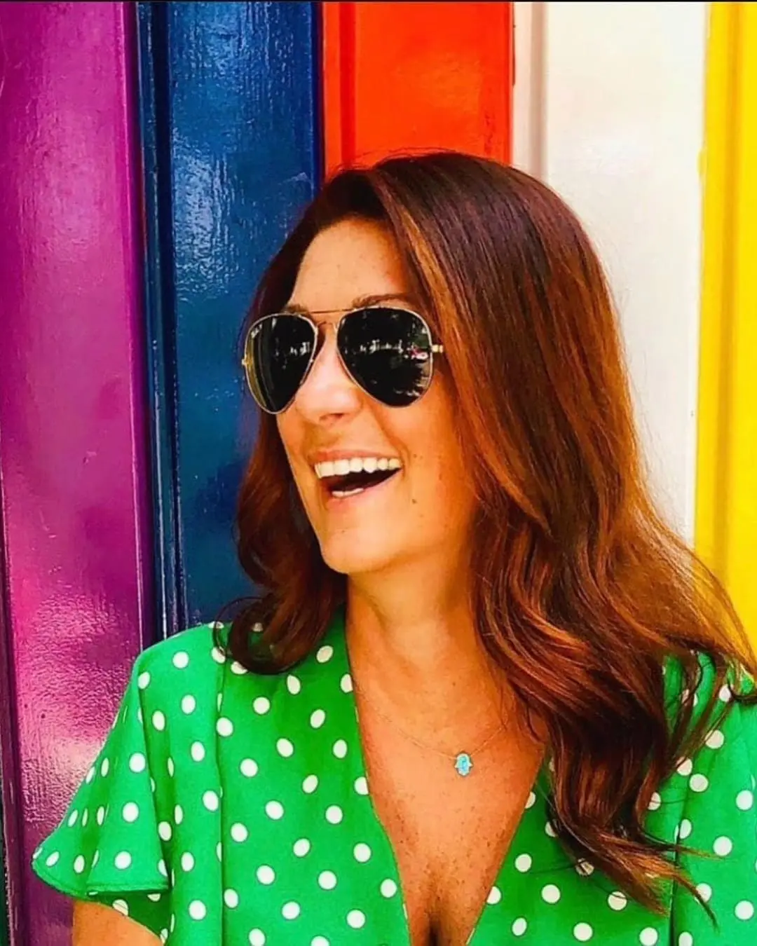 A smiling woman outdoors with long, vibrant auburn red hair styled in soft cascading waves, featuring custom color by Lisa Edwards at Sunday Salon in Raleigh, NC.