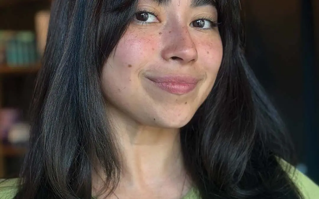 Medium-length, glossy espresso brunette hair styled with a smooth blowout, soft layers, and wispy curtain bangs, expertly cut by a stylist at Sunday Salon in Raleigh.