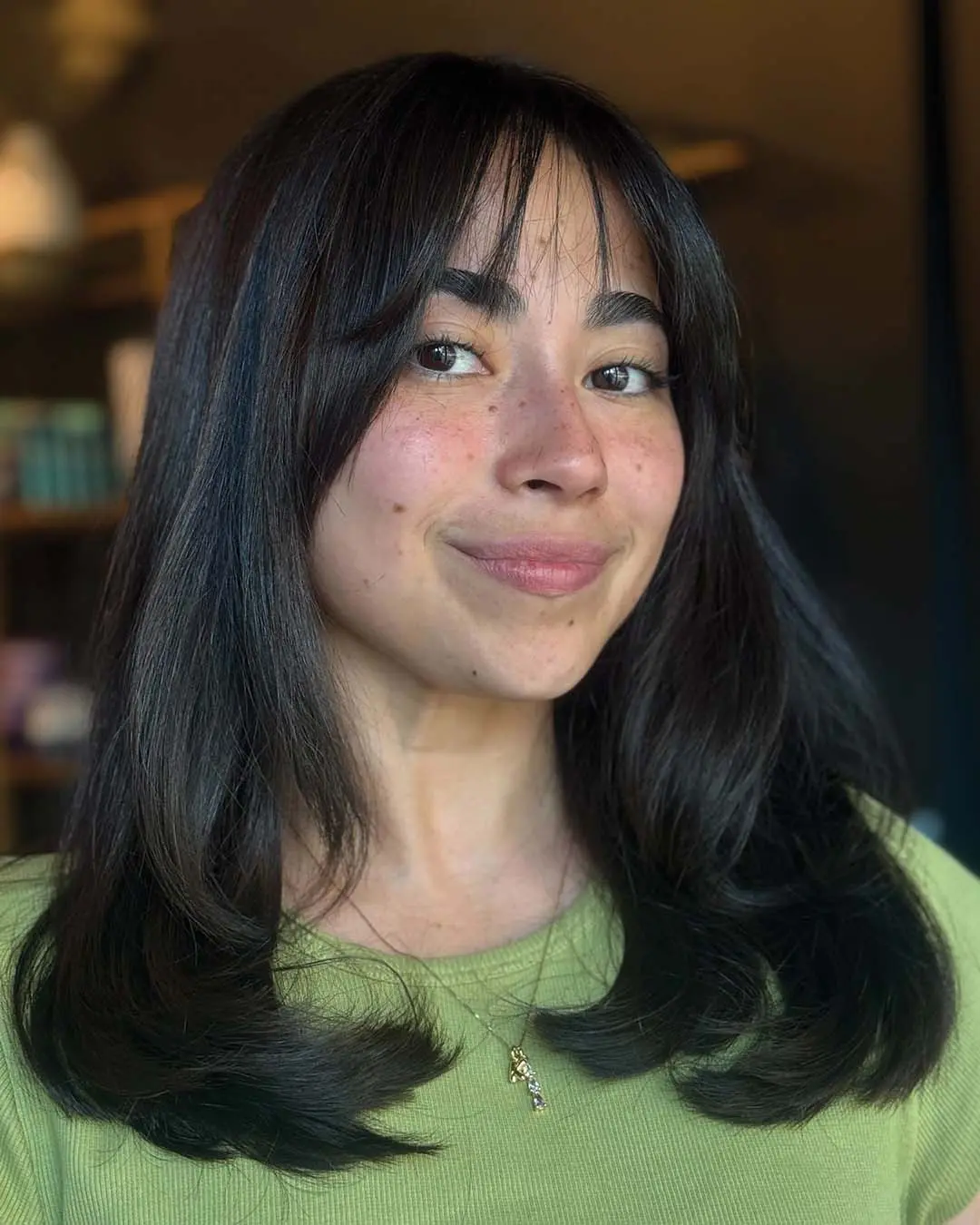 Medium-length, glossy espresso brunette hair styled with a smooth blowout, soft layers, and wispy curtain bangs, expertly cut by a stylist at Sunday Salon in Raleigh.