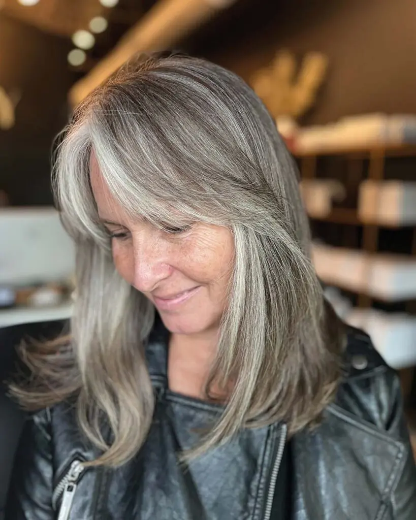 Sophisticated Silver Grey Blending with Soft Face-Framing Layers Medium-length sleek hair showcasing a sophisticated silver grey blending transformation with bright, face-framing highlights, crafted by an expert stylist at Sunday Salon in Raleigh.