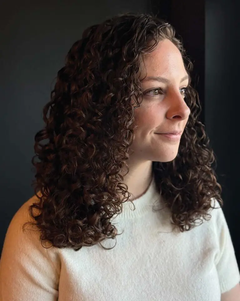 Medium-length, naturally curly hair styled with perfectly defined, bouncy ringlets in a rich chocolate brown hue with warm undertones, expertly shaped by a stylist at Sunday Salon in Raleigh.