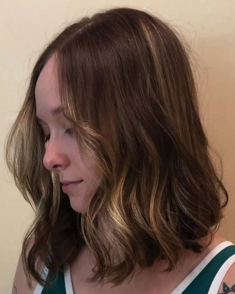 Dimensional Warm Honey Lob with Soft Effortless Waves A shoulder-length lob with rich brunette base tones, soft warm honey money piece framing, and lived-in waves created at Sunday Salon in Raleigh.