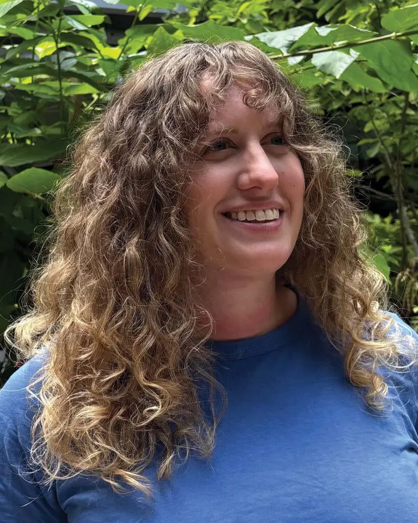 Naturally Defined Golden Blonde Curls with Curly Fringe A long, naturally curly hair transformation featuring defined golden blonde ringlets and full curtain bangs created at Sunday Salon in Raleigh.