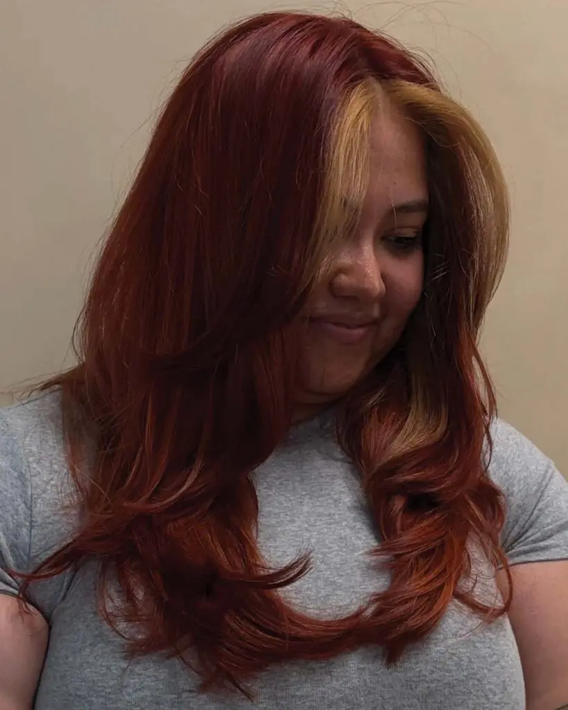 Vivid Copper Red with Contrast Golden Blonde Face-Framing Money Piece A long copper red hair transformation featuring a bold warm golden blonde face-framing money piece and bouncy curled layers, created at Sunday Salon in Raleigh.
