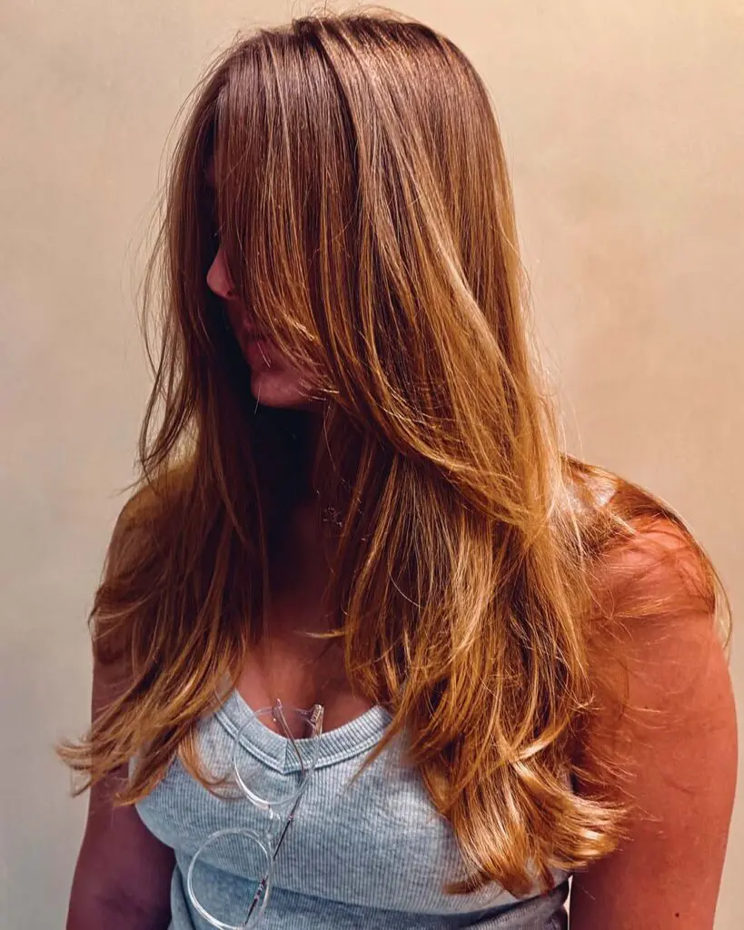 Warm Warm Honey Gold Blonde with Soft Curled-Under Layers A long warm honey gold blonde haircut styled with soft, curled-under face-framing layers and natural golden dimension, created at Sunday Salon in Raleigh.