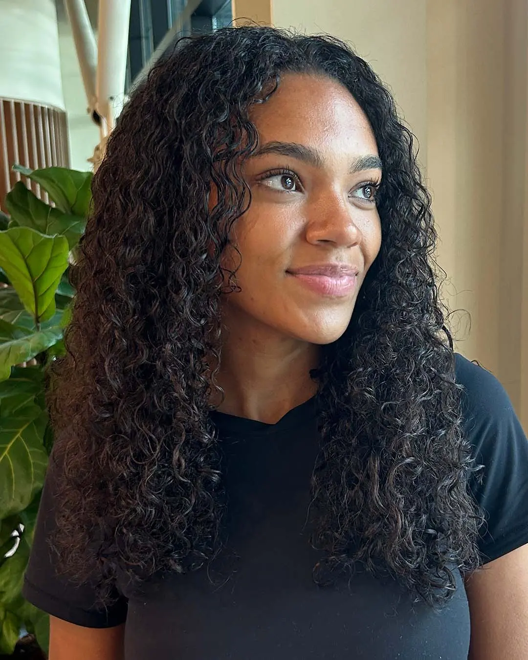A woman showcasing long, cascading deep espresso natural curls with incredible ringlet definition styled at Sunday Salon in Raleigh.