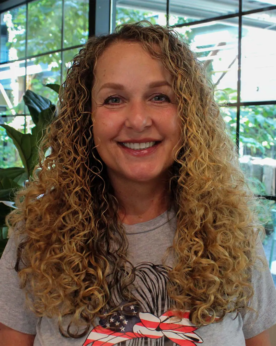 Shoulder-length blonde hair with extremely defined, springy curls and lighter highlights, created by expert stylists at Sunday Salon in Raleigh.